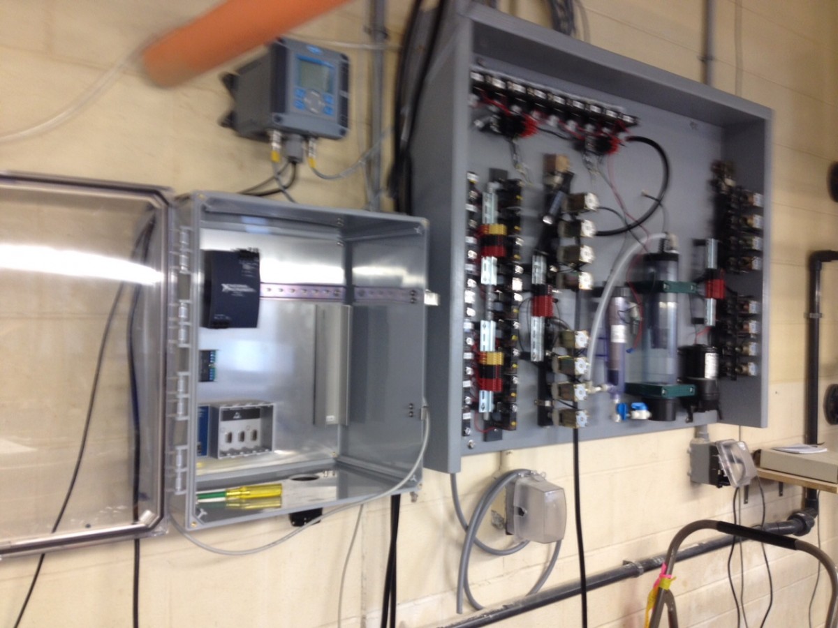 The main board of the system, not fully assembled, sporting lots of solenoid valves, flow cells, whereas the controller for pH and DO sits atop the still empty electronics box.